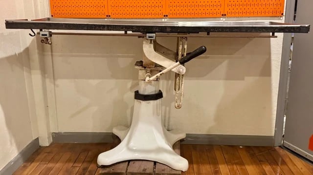 Figure 3 — An early-twentieth-century cast-iron and porcelain-enameled embalming table, empty, showing the tilting top and drainage channel that replaced the perforated wooden board.