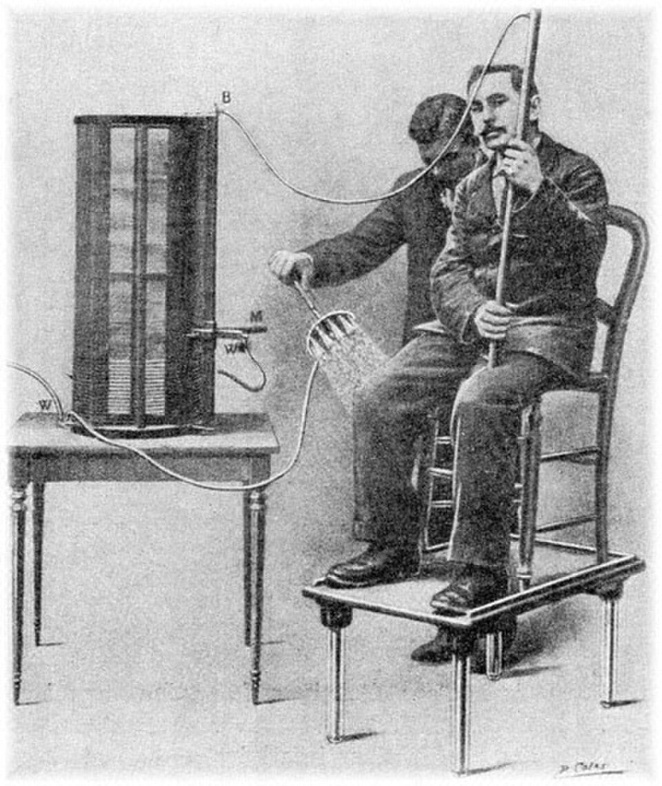 Figure 2 — Period engraving of an autoconduction session: a seated patient inside the great solenoid, the apparatus and its operator alongside. The patient is in the circuit but touches no electrode.