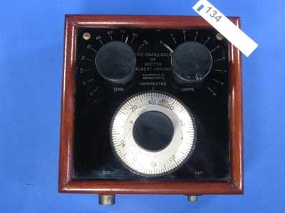 Figure 1 — An Abrams Oscilloclast treatment box: a portable wooden or Bakelite case with a hinged lid, a front panel of numbered dials, rheostats and push-buttons, and terminal posts for the wire leads — the …