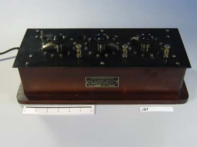 Figure 1 — An Abrams Oscilloclast: a wooden cabinet of dials, rheostats, and terminals leased to practitioners under a contract that forbade opening it. Displayed here as an object of medical-fraud history, n…