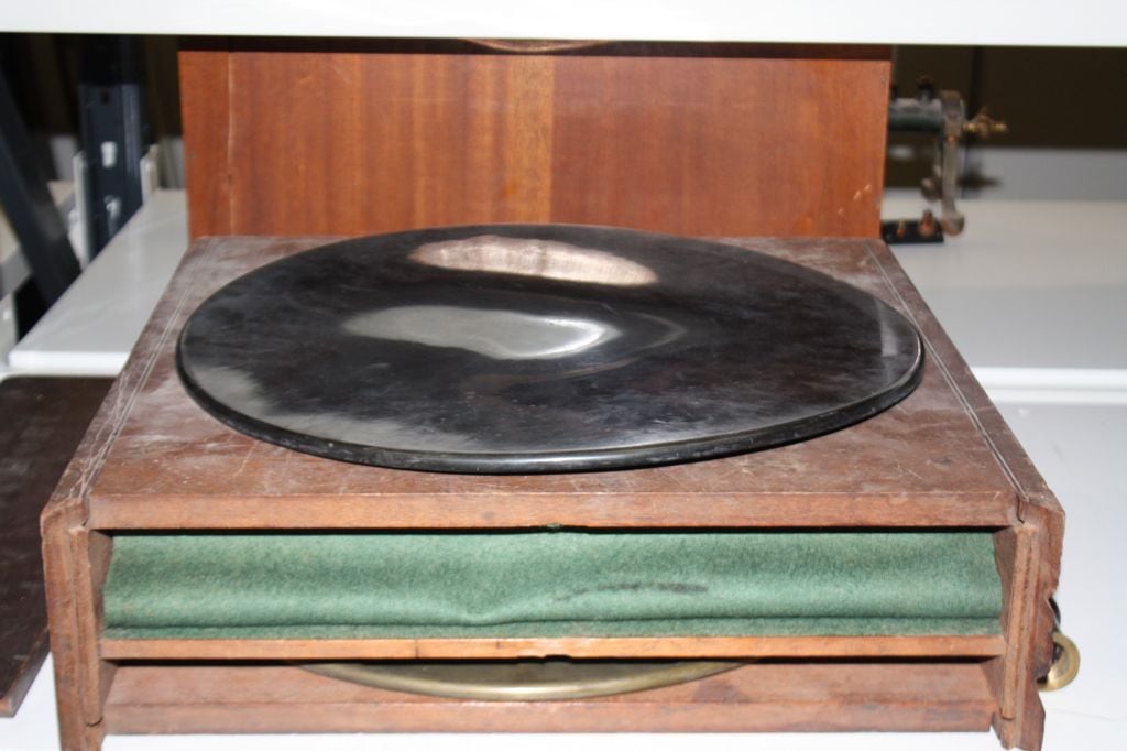 Figure 3 — The collector's warning sign: an ebonite disc gone brown and greasy with sulphur bloom, its foil sectors corroded and lifting — surface degradation that can render the disc partly conductive and un…