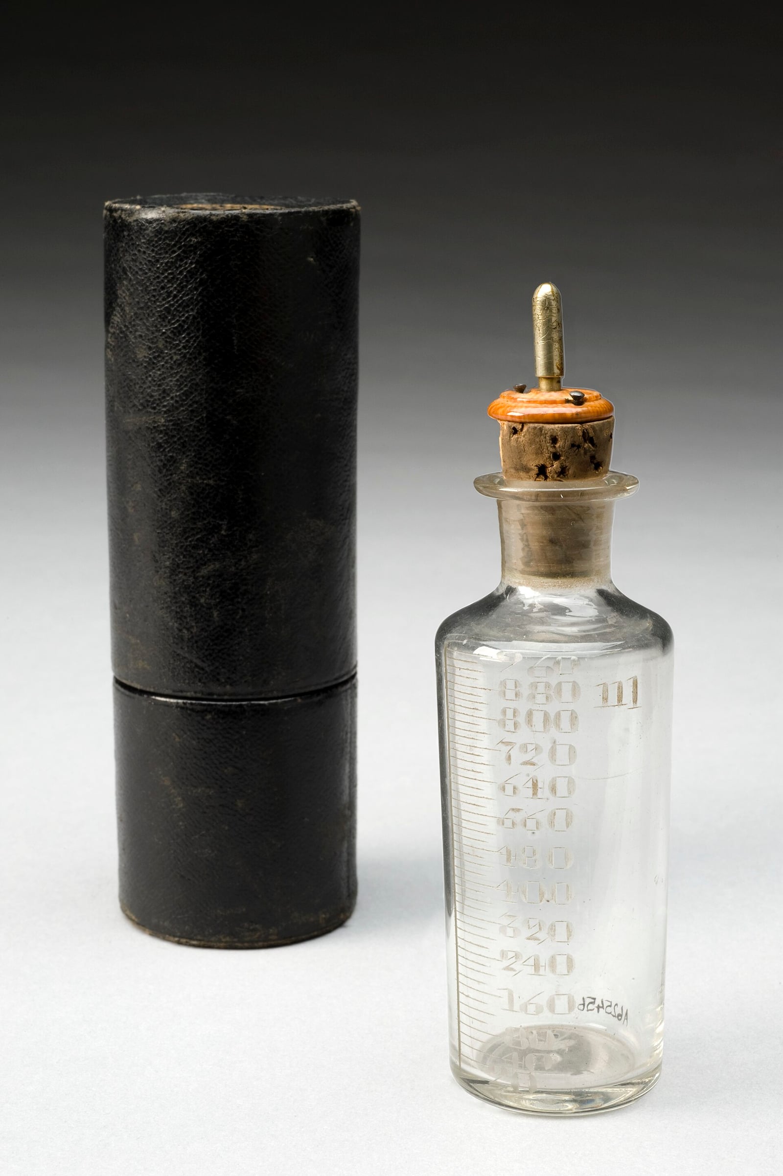 Figure 4 — A graduated chloroform dropper bottle, London, 1870–1900, with its japanned travelling case. The graduations and the metal dropper cap are the entire technology of the open method — which is exactl…