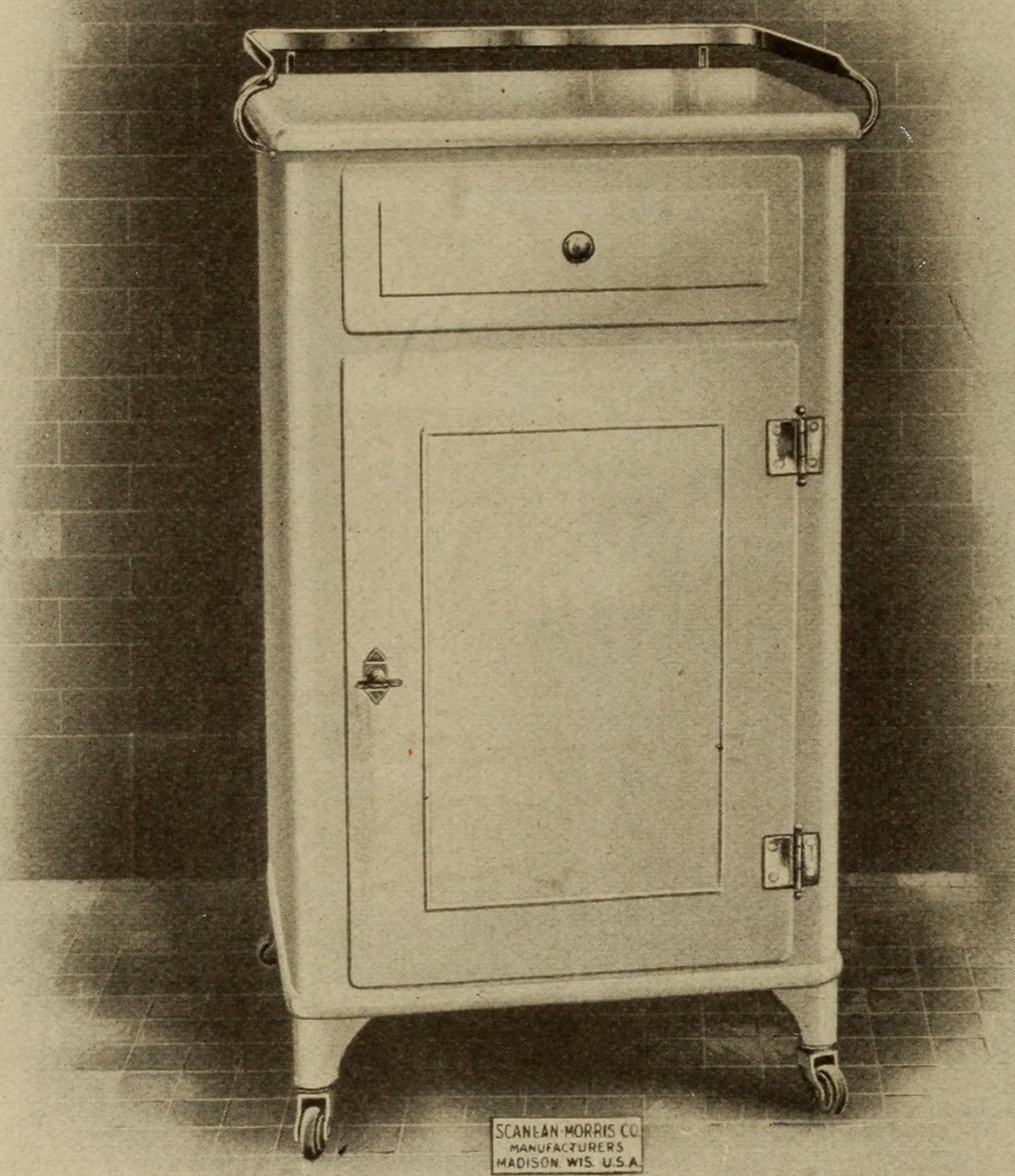 Figure 2 — An instrument cabinet as the trade sold it — enamelled steel on castors, a single wipeable door and drawer, no crevice and no porous surface anywhere. Scanlan-Morris Co., Madison, Wisconsin. This i…