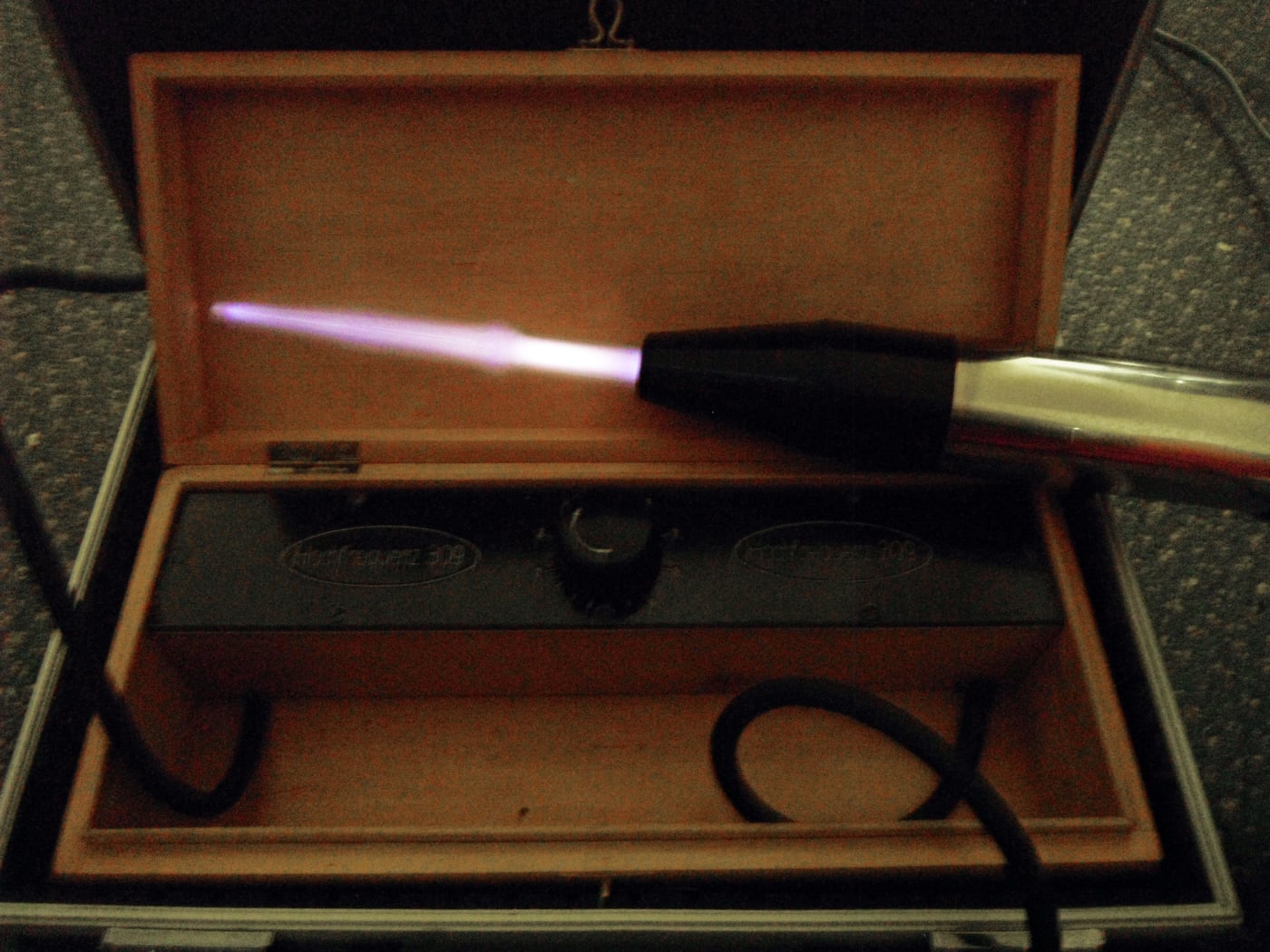 Figure 3 — A violet-ray electrode lit in a darkened room, the characteristic violet gas-discharge glow that gave the device its name — and its central deception.